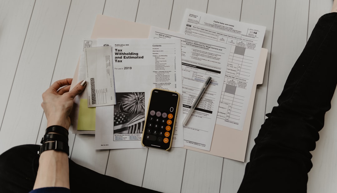 Person calculating debt consolidation loan payments with a calculator and bills
