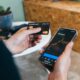 Improve your credit score fast: person checking credit card and score on smartphone