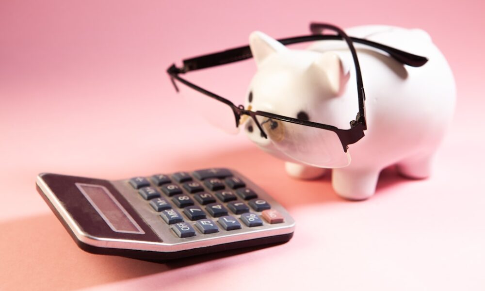 Calculator and piggy bank illustrating the decision to pay off debt or invest first