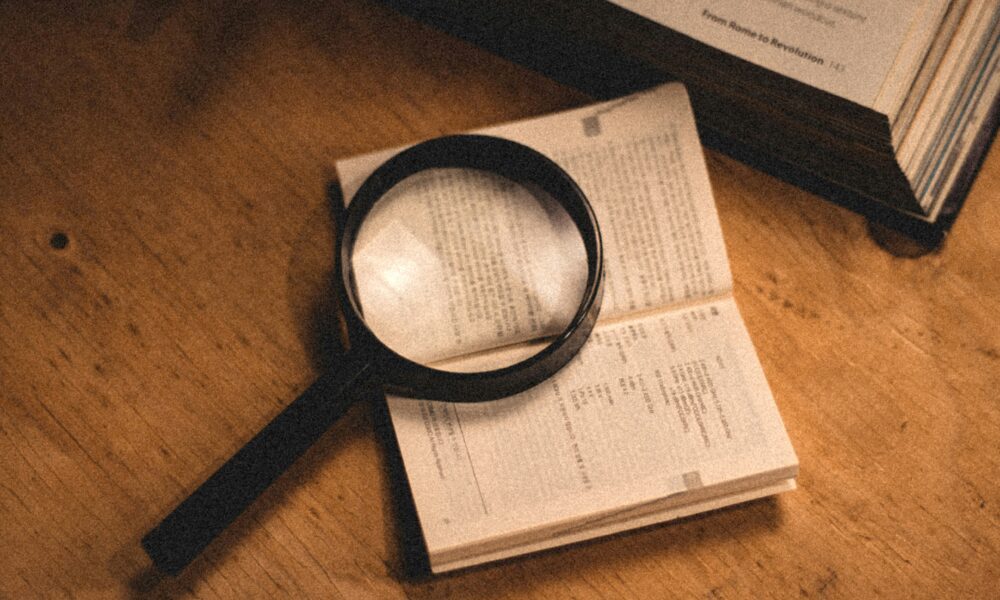 FICO score vs VantageScore comparison shown with a credit report and magnifying glass