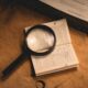 FICO score vs VantageScore comparison shown with a credit report and magnifying glass